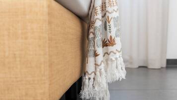 A close-up of a textured beige sofa with a white and brown patterned throw blanket draped over it.