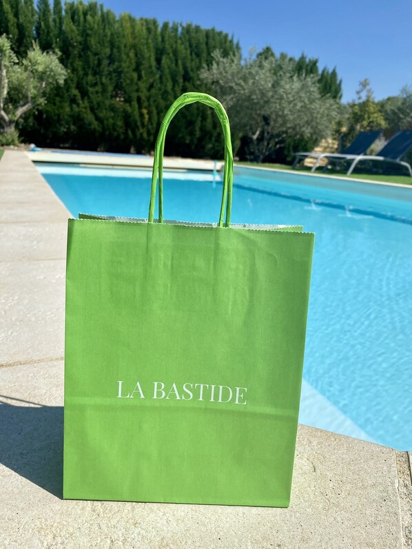 Una bolsa de tela verde con el texto "LA BASTIDE" colocada junto a una piscina.