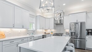 Una cocina moderna con armarios blancos, electrodomésticos de acero inoxidable y una isla grande con taburetes de bar.