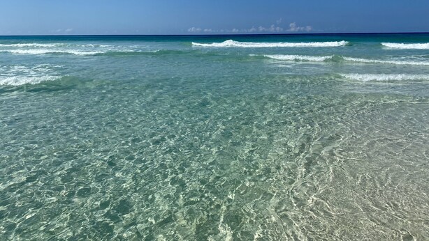 Una playa con aguas cristalinas y olas suaves.