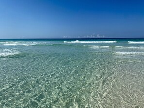 Une plage avec une eau claire et peu profonde et de douces vagues.
