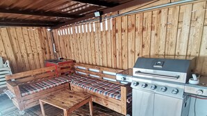 A rustic wooden interior with a bench, a table, and a built-in grill station. - RURAL HOUSE  (Yebra)
