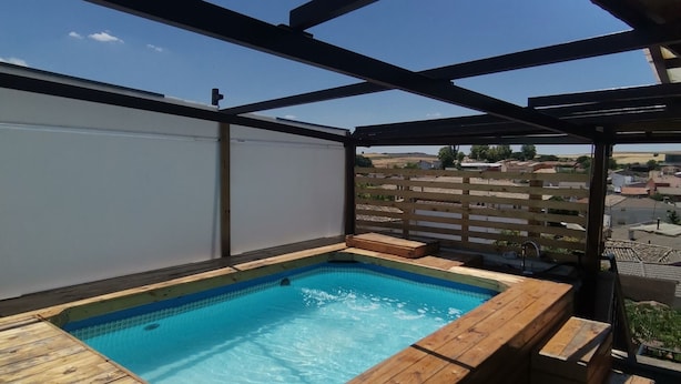 A wooden hot tub with a clear blue pool, surrounded by a wooden deck and a pergola structure. - RURAL HOUSE  (Yebra)