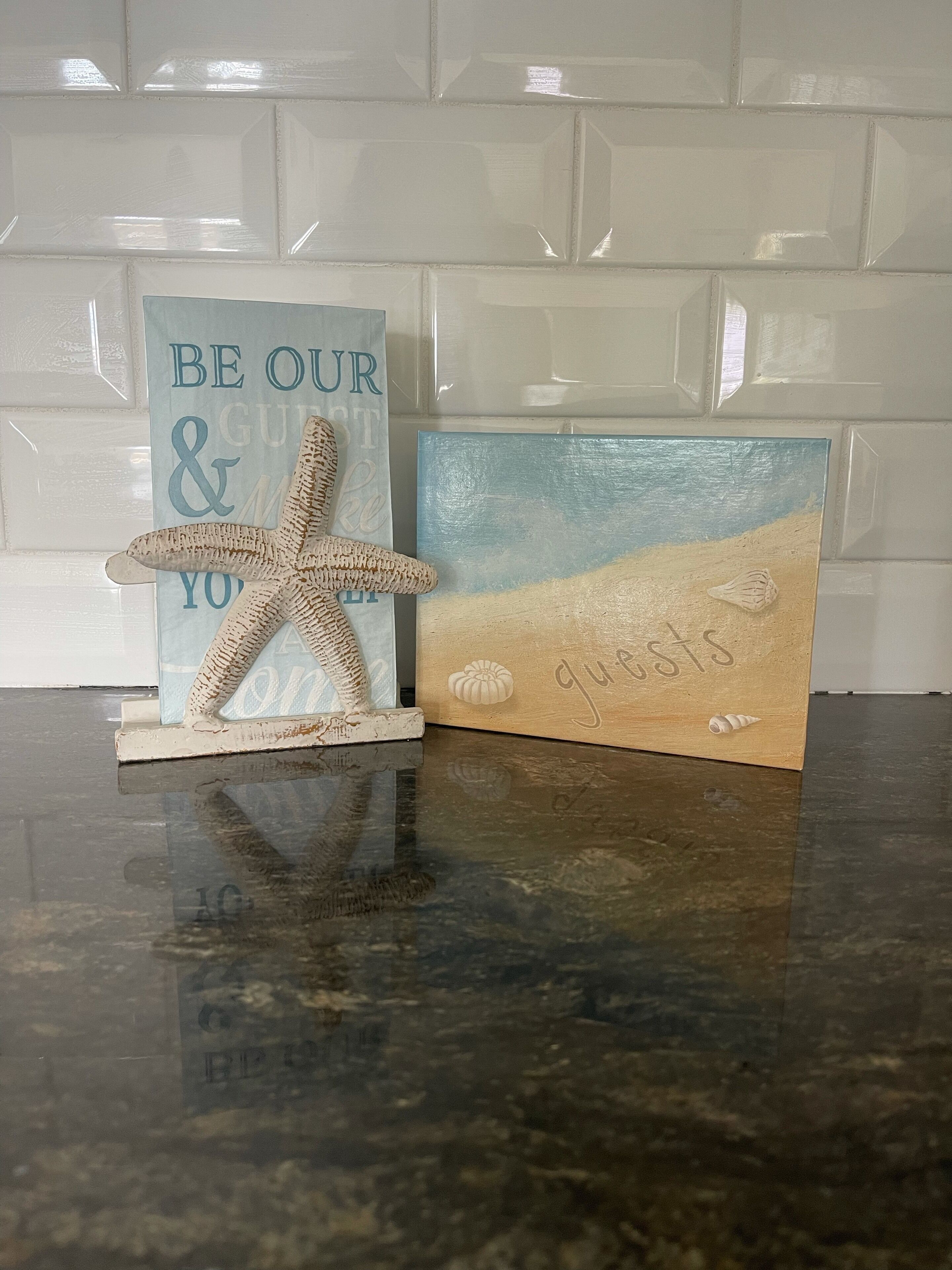 Uma bancada de cozinha com uma estrela-do-mar decorativa e um cartão com tema praiano.