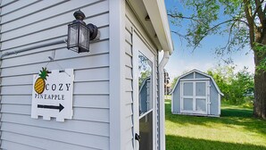 Una casa con un cartel que dice "COZY PINEAPPLE" y un cobertizo pequeño en el jardín.