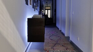 Un couloir doté d’un sol carrelé, d’un tapis et d’un banc de couleur sombre.