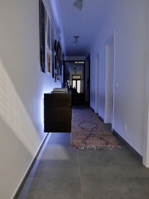 A hallway with a tiled floor, a rug, and a dark-colored bench.