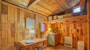 Un chalet confortable avec un intérieur en bois, une table à manger avec des chaises, un petit coin cuisine et un panier à linge.