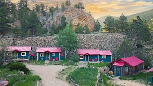 Un ensemble de chalets aux toits rouges, entourés d’un paysage naturel agrémenté d’un mur de pierres et d’arbres.