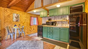 A cozy kitchen with wooden walls, green cabinets, and a black refrigerator. - Vintage Riverside Cabin — Spacious Family Stay (Lyons)