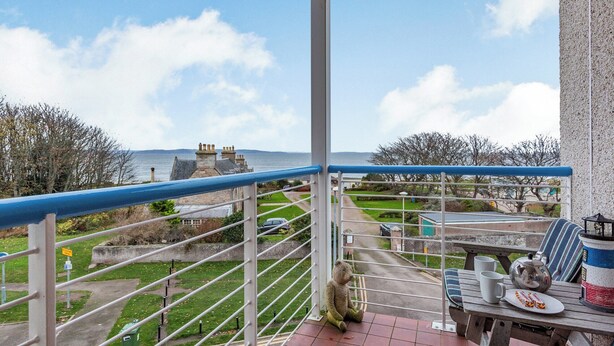 Un balcon avec vue sur la mer, une table avec un ours en peluche et un coin pique-nique aménagé.
