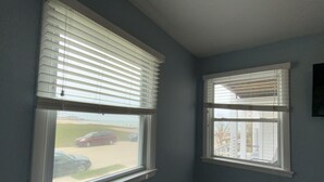 Two windows with blinds, a hallway, and a view of a parking lot with cars. - BEACHSIDE GETAWAY IN SHEBOYGAN (Sheboygan)