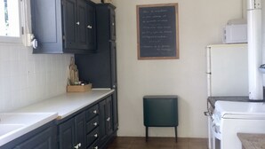 Eine Küche mit dunklen Schränken, einer weißen Arbeitsplatte, einer Tafel mit Schrift und einem kleinen Hocker.