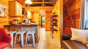 Interior de una cabaña de madera con cocina, comedor y sala de estar.