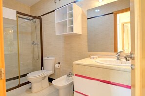A bathroom with a toilet, bidet, and a sink with a mirror above it. - Apartamento Cala Bajo by Solset (Nerja)