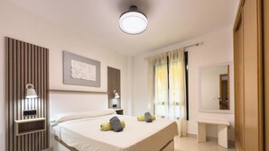 Habitación de hotel moderna con una cama grande, lámparas de noche, mesitas de noche, un espejo y una ventana con cortinas.