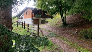 En enkel stuga med träfasad, en veranda och en inhägnad trädgård.