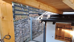 En pergola av trä med en mur av sten och en grind av metall.