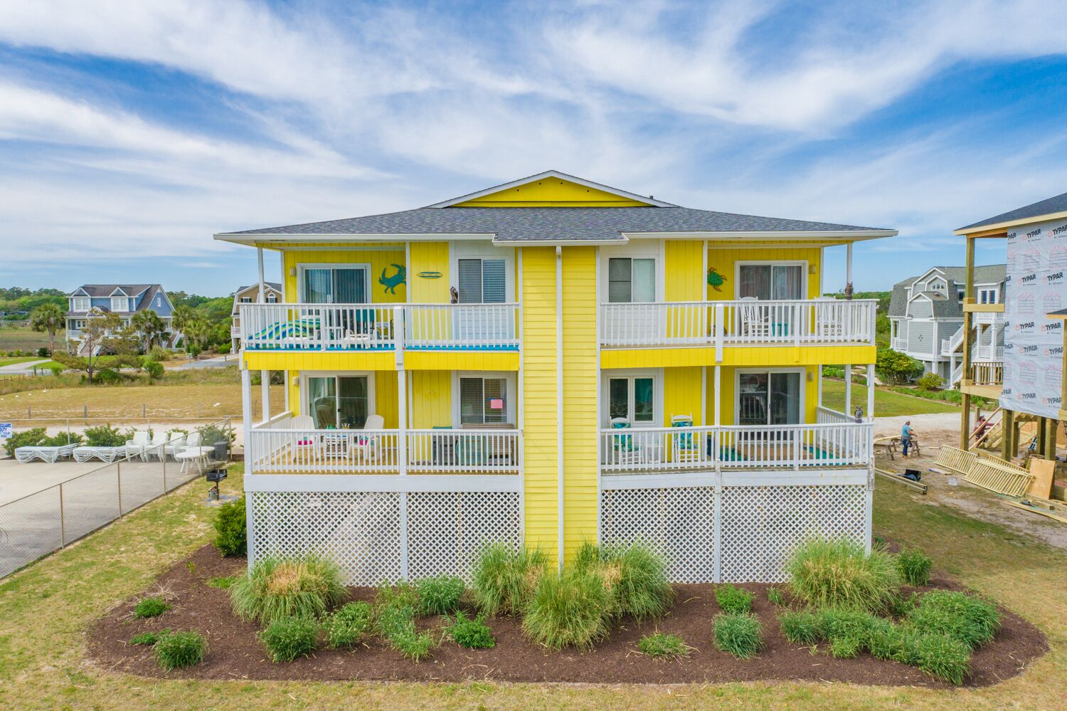 Un bâtiment jaune à deux étages, doté de balcons, entouré d’une clôture et agrémenté d’un aménagement paysager.