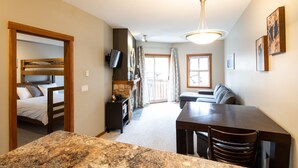 A room with a bunk bed, a fireplace, a television, a dining table, and a sofa. - Ski in, Ski out Fireside Retreat  (Sun Peaks)