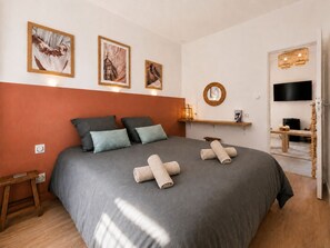 A bedroom with a large bed, a bedside table, a TV, and a wall-mounted shelf. - The Hacienda - Patio Terrace - Downtown / Beach 5 min (Le Havre)