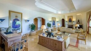 A spacious living room with a fireplace, a dining area with a wooden table and chairs, and a seating area with a sofa and armchairs. - Palatial Villa in Hacienda Las Chapas, Marbella (Marbella)