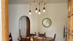 Un comedor con una mesa redonda, sillas de madera, un tapete estampado, un reloj de pared y una puerta de madera.