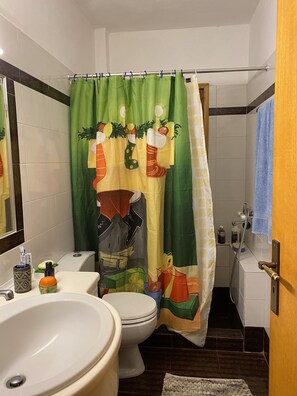 A bathroom with a toilet, sink, and shower curtain with a festive design.