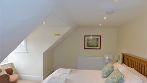 A bedroom with a bed, a chair, a radiator, a ceiling fan, and a framed picture on the wall. - Clarendon -  a house that sleeps 10 guests  in 5 bedrooms (Sheringham)