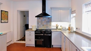 A compact kitchen with a gas stove, oven, and a patterned backsplash. - Clarendon -  a house that sleeps 10 guests  in 5 bedrooms (Sheringham)