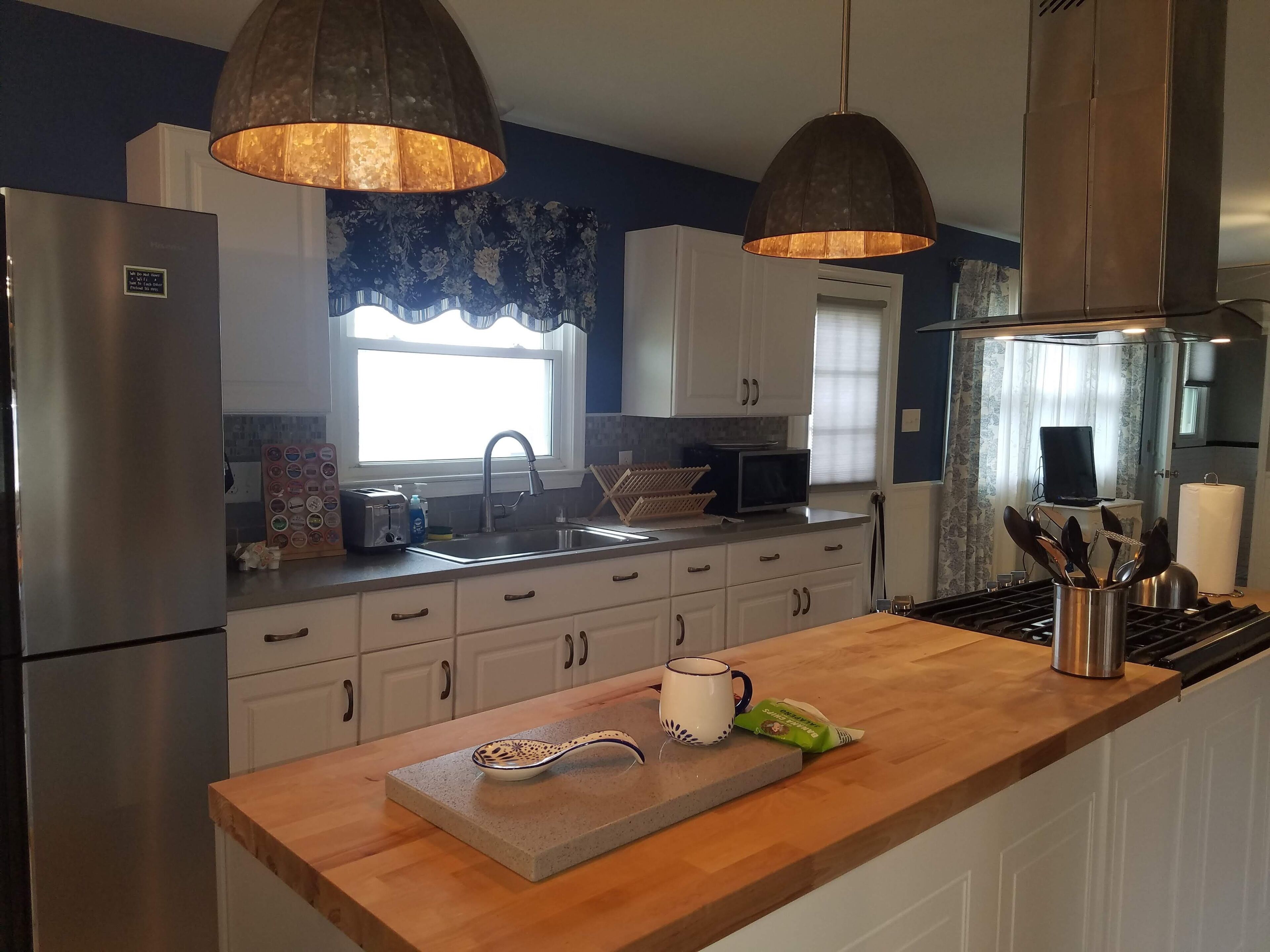 Une cuisine moderne dotée d’appareils électroménagers en acier inoxydable, d’un plan de travail en bois et de luminaires suspendus.