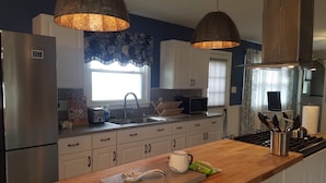 Una cocina moderna con electrodomésticos de acero inoxidable, una encimera de madera e iluminación colgante.