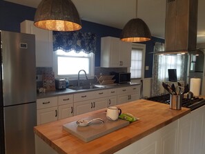 Una cucina moderna con elettrodomestici in acciaio inossidabile, un piano di lavoro in legno e illuminazione a sospensione.