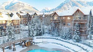 Un resort con piscina, alberi innevati e vista sulle montagne.