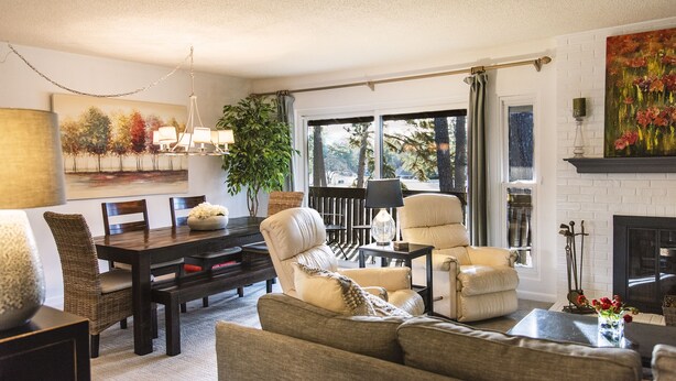 Un salon comprenant une table à manger en bois foncé, deux fauteuils en cuir, un canapé, une table basse et une cheminée.