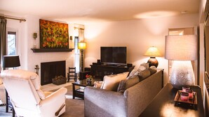 Un salon avec une cheminée, un canapé, un téléviseur et une lampe.