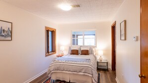 Une chambre à coucher avec un lit, une fenêtre, une table de chevet et une porte.