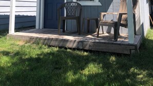 A small cabin with a blue door, a window, and a porch with two chairs. - Teakettle Kabin Tiny Home (Columbia Falls)