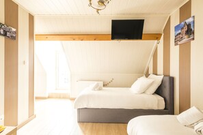 Une chambre à coucher avec un lit, un téléviseur fixé au mur et une fenêtre.