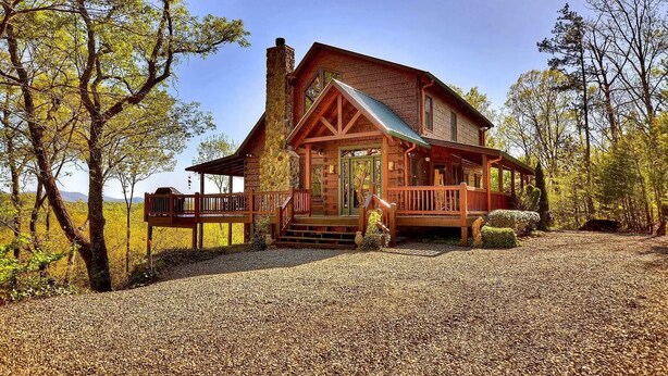 Eine rustikale Holzhütte mit einem Steinkamin, einer Holzdiele und einer Veranda.