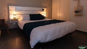 Un dormitorio moderno con cama, lámparas de noche, una silla y un perchero para sombrero y bolso.