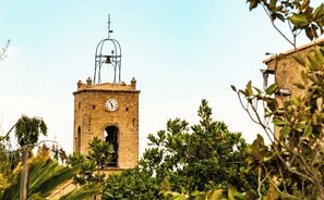 A stone tower with a clock, surrounded by greenery.