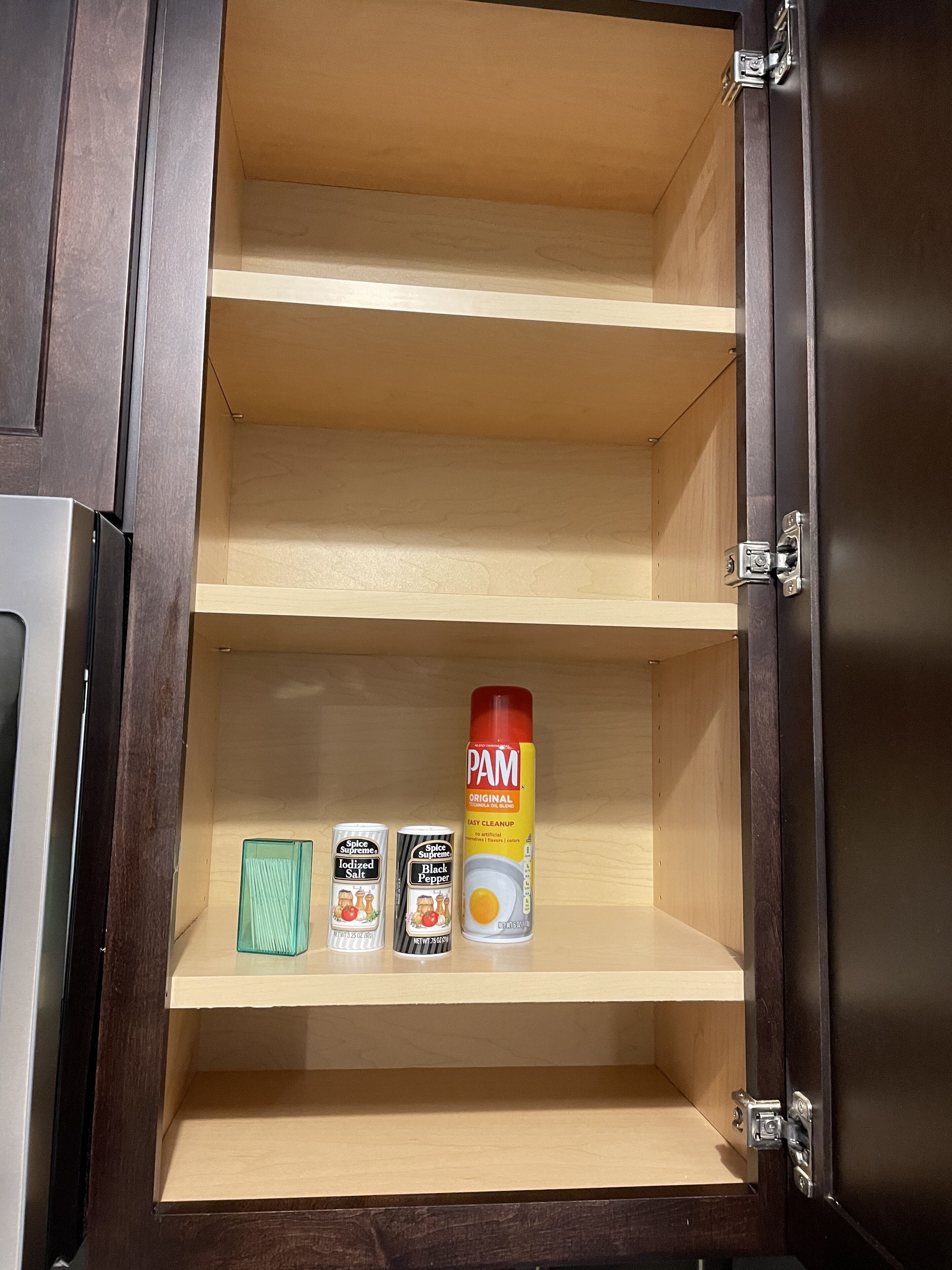 Un mueble de madera con tres repisas, cada una con un recipiente para especias.
