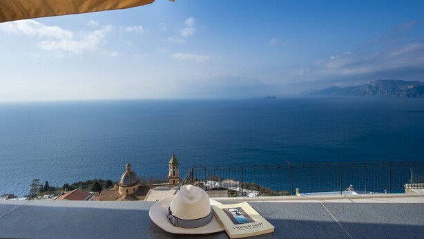 A coastal view with a book and a hat on a ledge, overlooking the sea and a church. - Villa Cimino - Central Villa Stunning Sea View (Praiano)