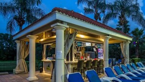 A covered outdoor seating area with lounge chairs and a bar. - Extended Stay Retreat – Private Pool, Spa & Space for Everyone  (Kissimmee)
