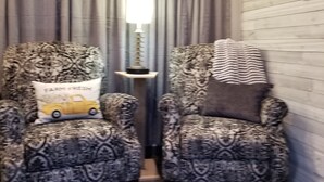 Two armchairs with patterned upholstery, a lamp, and a window with a view of trees.