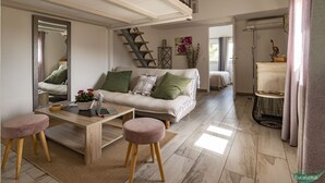 A modern living room with a sofa, coffee table, and a staircase leading to an upper level. - L'Eucalyptus, mazet not overlooked, beautiful private outdoor space (Le Plan-de-la-Tour)