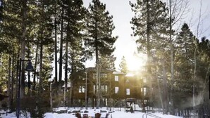 A pool surrounded by snow-covered ground and tall pine trees, with a building in the background. - 2 bedroom Condo at Hyatt Lake Tahoe - May 29th - June 4th (Incline Village)
