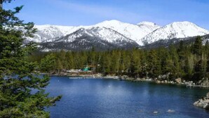 A lake with mountains in the background, surrounded by trees and a small building. - 2 bedroom Condo at Hyatt Lake Tahoe - May 29th - June 4th (Incline Village)