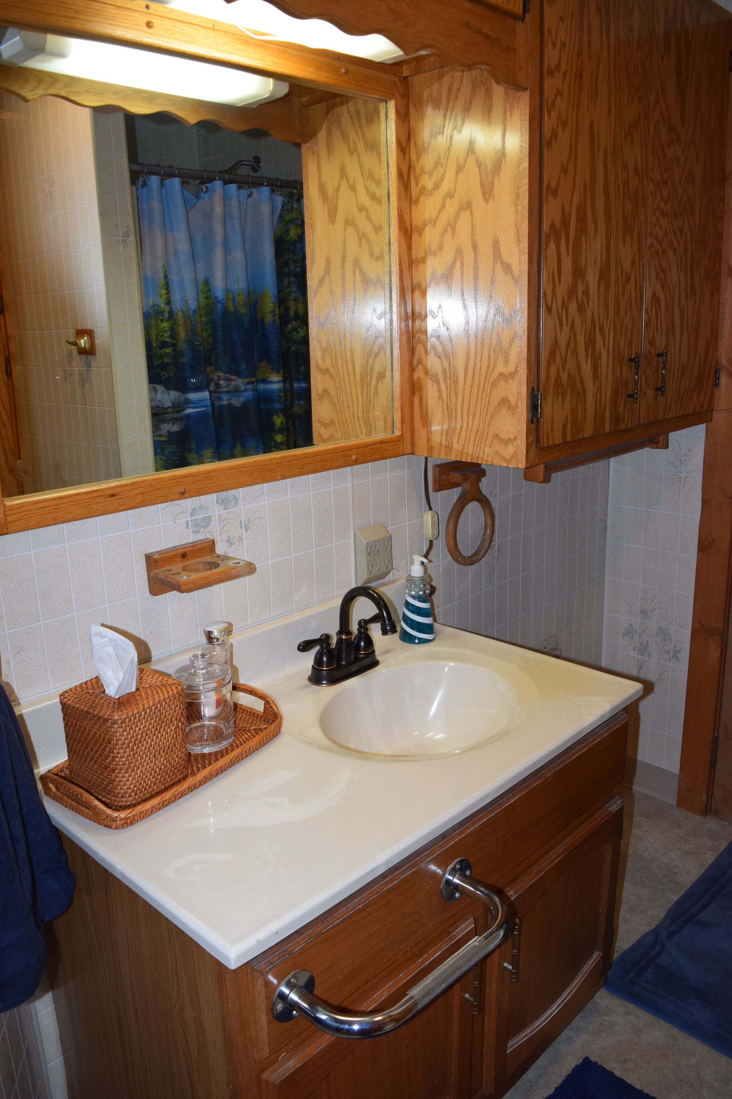A bathroom with wooden cabinets, a white sink, and a mirror above it.